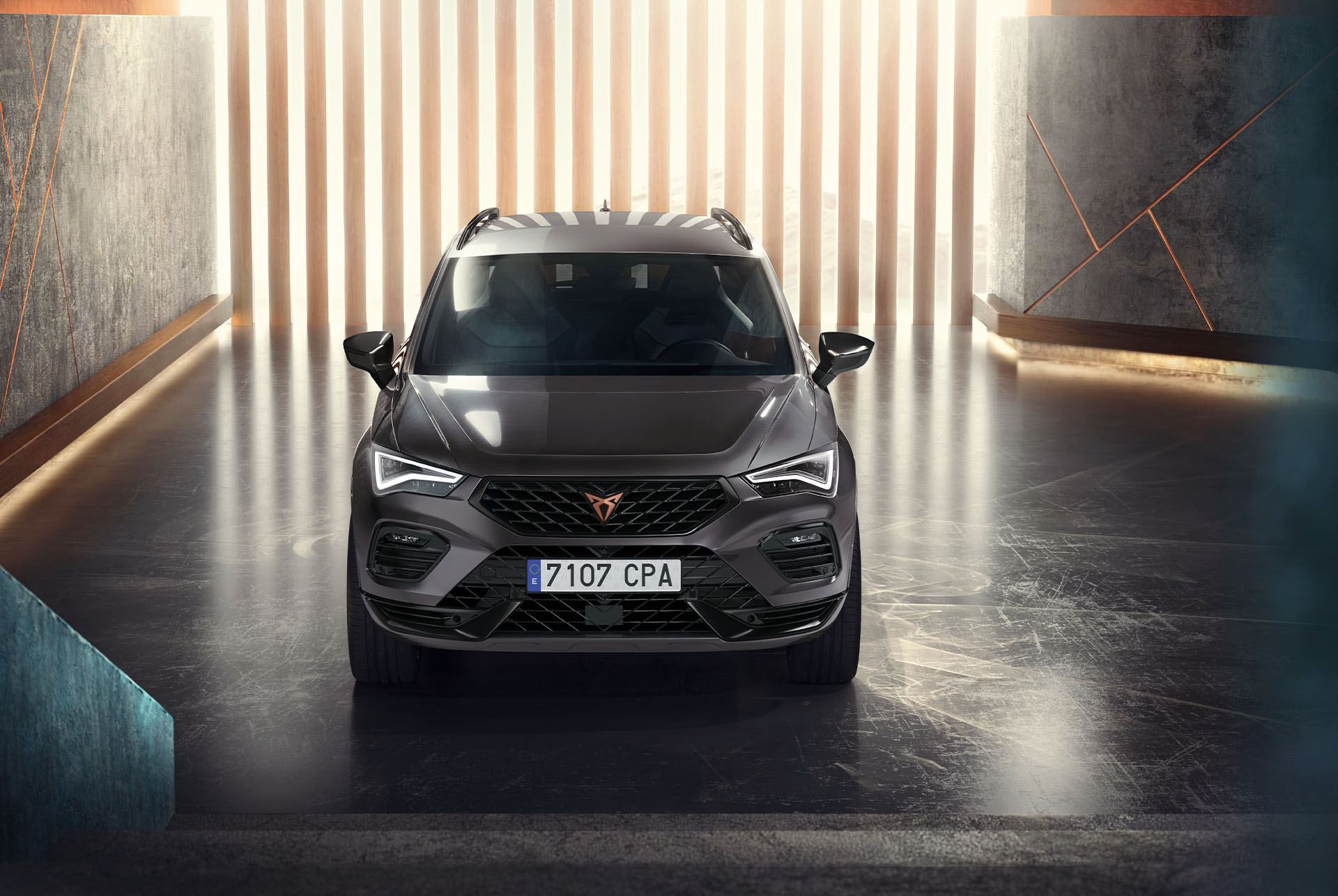 Cupra Ateca, en grå SUV, sedd framifrån i en modern, upplyst miljö. 