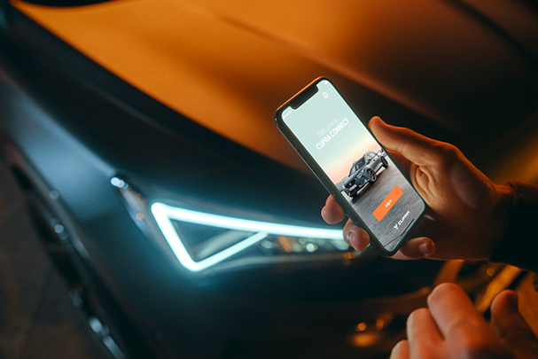 kvinna med cupra connect-appen öppen bredvid en bil